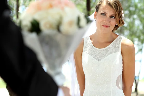 Schöne Braut lächelt und schaut zu ihrem Bräutigam — Stockfoto