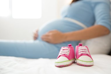 bir çift hamile bir kadın, odak o yanında pembe yürümeye başlayan çocuk spor ayakkabı