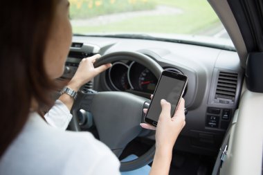 Arkadan alınan bir arabanın içine cep telefonu kullanan kadın