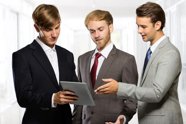 Tres jóvenes empresarios discuten sobre algo en una tableta — Foto de Stock
