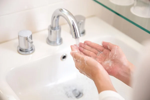 Lavar as mãos com sabão sob água corrente, as mãos da mulher — Fotografia de Stock