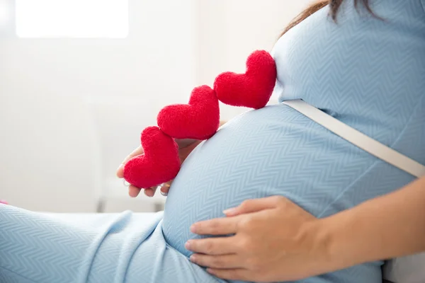 Asian young pregnant woman put heart shape accessories in her tu — Stock Photo, Image