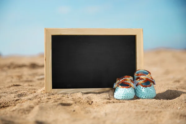 Chaussures pour tout-petits en tricot bleu et mini chalkwide, sable sur la plage b — Photo