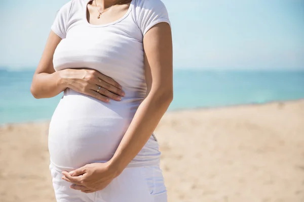 Vientre de mujer embarazada en la playa — Foto de Stock