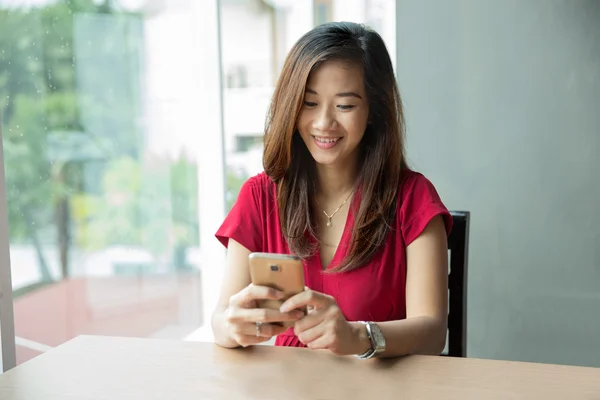 Asiatico donna holding un smartphone mentre avendo alcuni frutta — Foto Stock