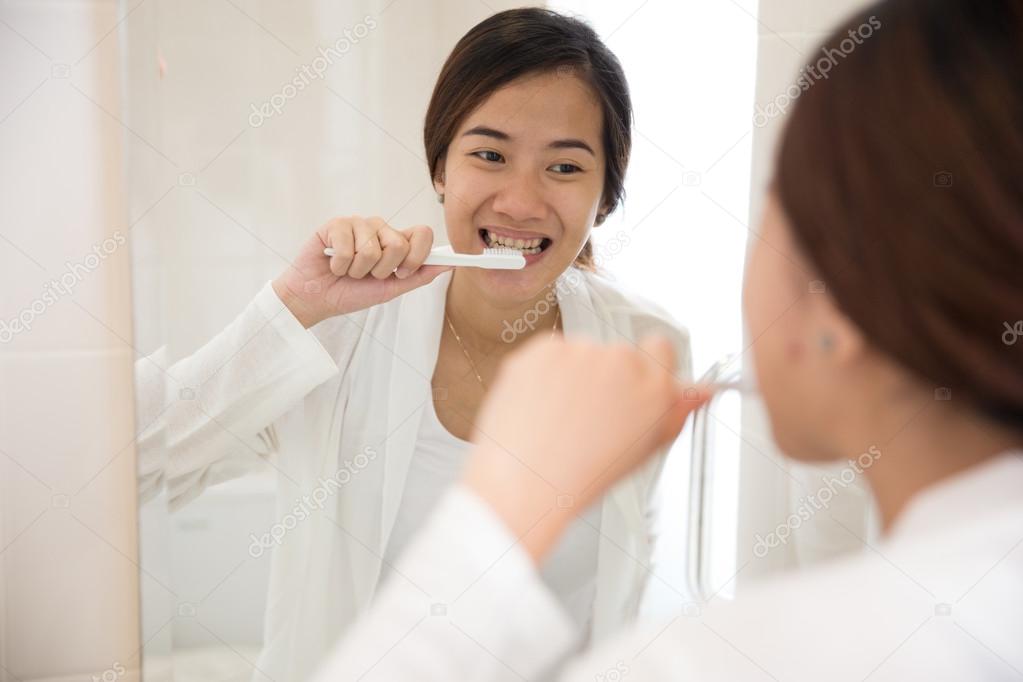 Beautiful asian woman brushing her teeth happily