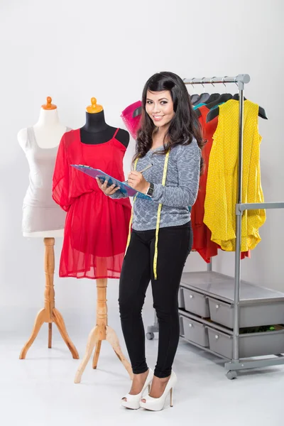 Unga asiatiska designer med ett urklipp står och ler — Stockfoto