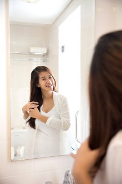 Asyalı kadın bir ayna önünde poz mutlulukla gülümseyerek