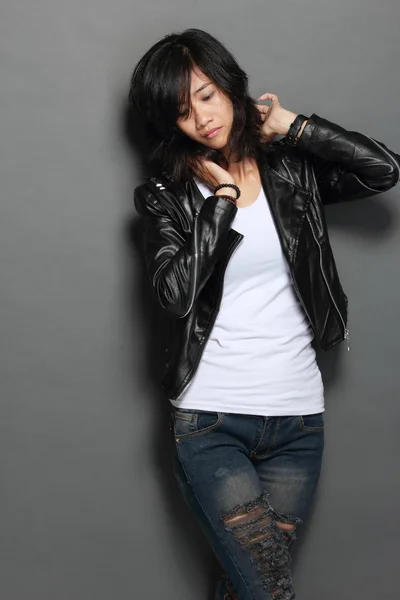 Asian young woman in black leather jacket on gray background — Stock Photo, Image