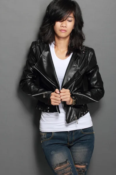 Asian young woman in black leather jacket on gray background — Stock Photo, Image