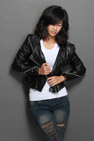 Asian young woman in black leather jacket on gray background — Stock Photo, Image