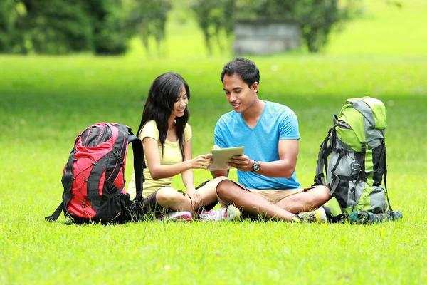 Unga asiatiska paret sitter på parken ser en TabletPC — Stockfoto