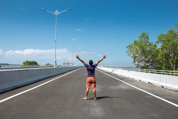 Man standing in the empty highway with both arms open, his back — Stock Photo, Image