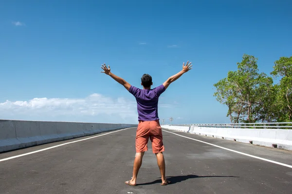 Man standing in the empty highway with both arms open, his back — Stock Photo, Image