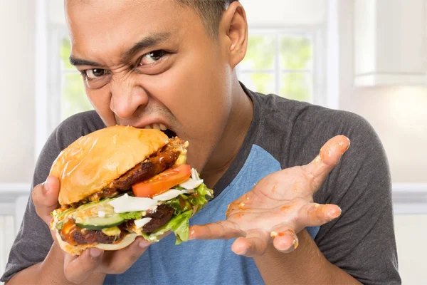 Young man bite his big burger deliciously — Stockfoto