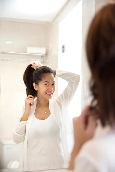 Gyönyörű ázsiai nő haját, miközben mosoly árukapcsolás a tükör — Stock Fotó