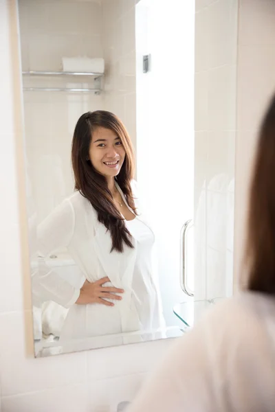 Asian woman posing in front of a mirror, smiling happily — Stock Photo, Image