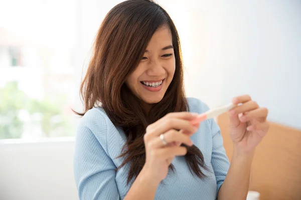 Asian young woman with a testpack in her hand, smiling happily — Stock Photo, Image