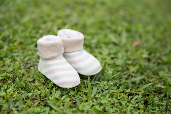 Blanco rayas grises tejen zapatos de niño en el patio de hierba — Foto de Stock