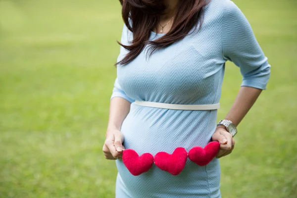 Asiática embarazada mujer en azul vestido celebración corazón forma accessori —  Fotos de Stock