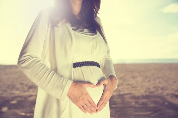 Беременная женщина с сердцем жестикулирует на букву б — стоковое фото