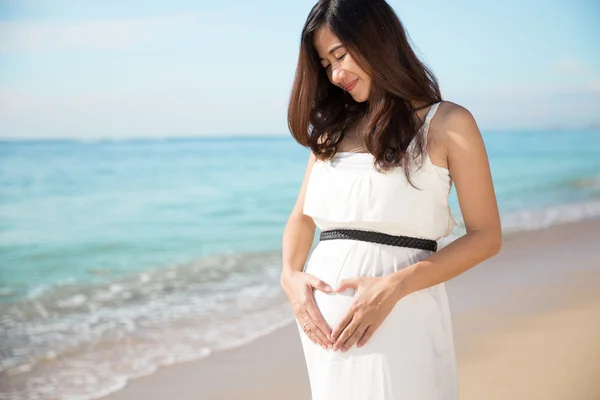 Asian pregnant woman make heart shape with hand on her stomach — Stock Photo, Image