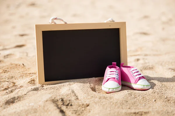 Paire de chaussures pour tout-petits et mini planche à craie sur le sable — Photo