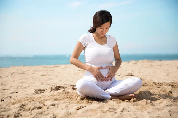 Embarazada asiática mujer haciendo yoga en el mar orilla —  Fotos de Stock