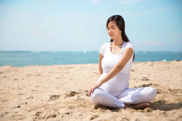 Embarazada asiática mujer haciendo yoga en el mar orilla — Foto de Stock