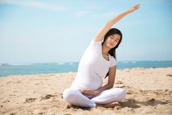 Pregnant asian woman doing yoga in the sea shore — Stock Photo, Image