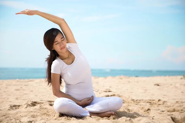 Embarazada asiática mujer haciendo yoga en el mar orilla — Foto de Stock