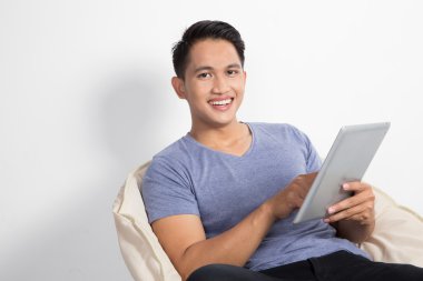 sandalyede otururken bir tablet tutan adam