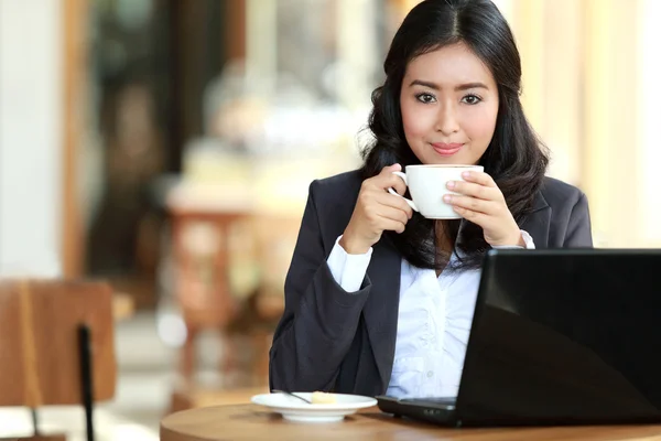 Mujer de negocios haciendo su trabajo mientras toma un descanso para tomar un café — Foto de Stock