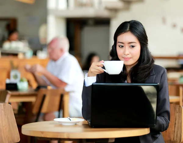 Бизнесвумен пьет кофе во время работы на ноутбуке — стоковое фото