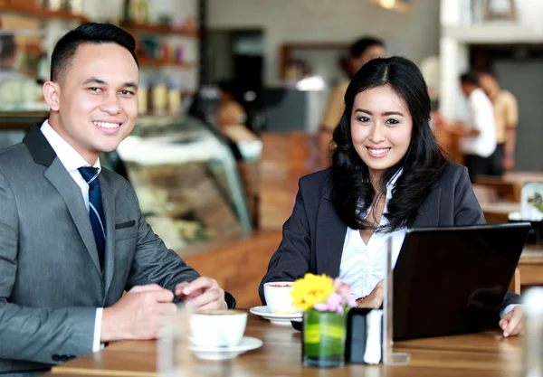 Pareja de negocios sonriendo y mirando a la cámara mientras se reúnen —  Fotos de Stock