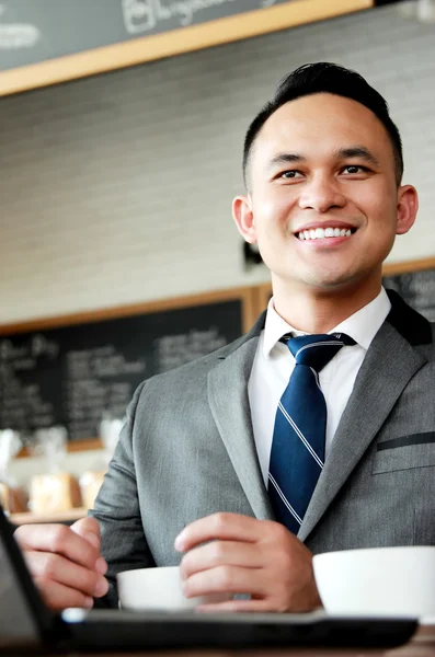 Hombre de negocios sonriendo mientras trabajaba en su portátil —  Fotos de Stock