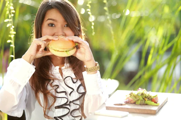 Aantrekkelijke vrouw bijten een hamburger — Stockfoto