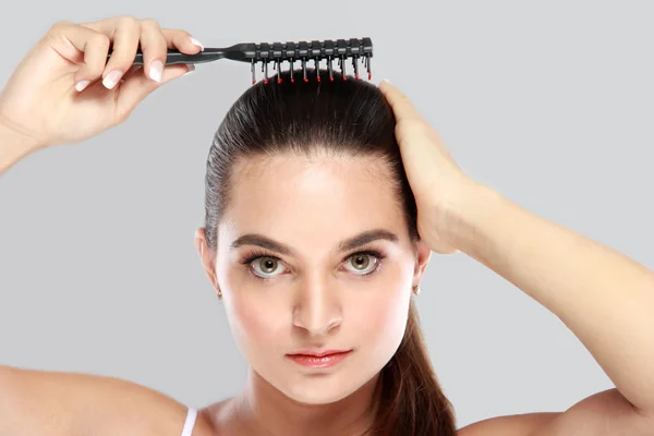 Hermosa modelo ordenar su cabello usando peine de pelo — Foto de Stock