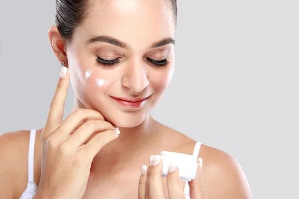 Beautiful woman applying some cream to her face — Stock Photo, Image