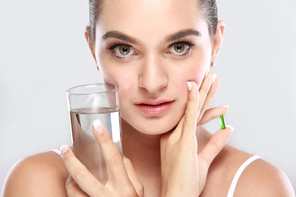 Aantrekkelijke vrouw poseren met een glas water en vitamine capsul — Stockfoto