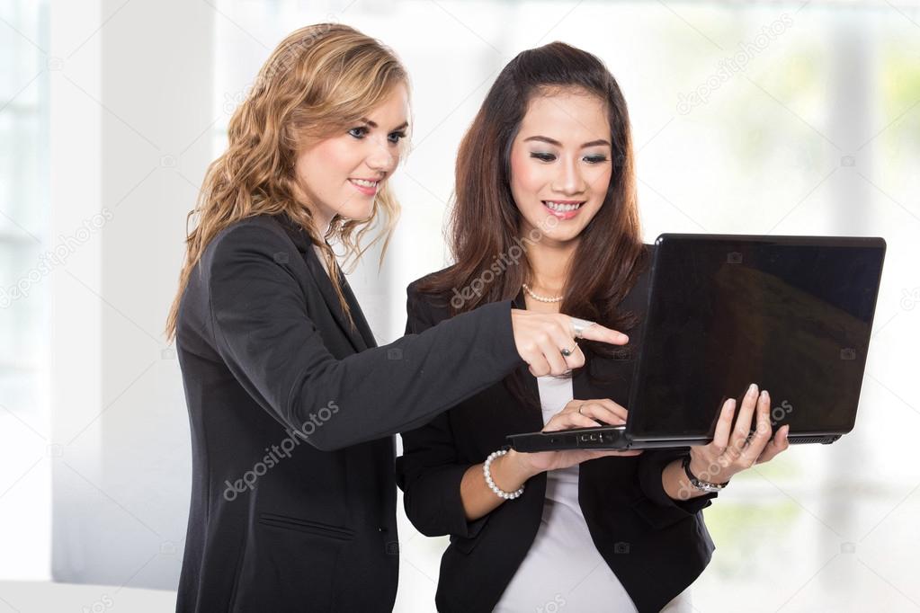Two businesswoman discussing something on the laptop