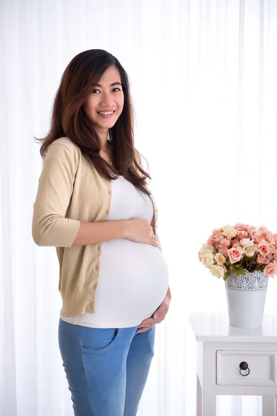 Счастливая красивая беременная азиатка смотрит в камеру — стоковое фото