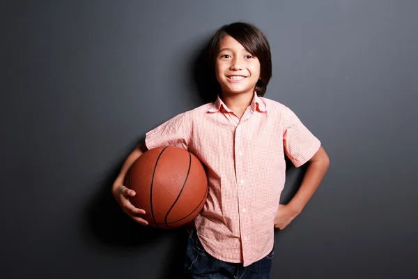 Добре виглядає хлопчик посміхається, тримаючи баскетбол — стокове фото