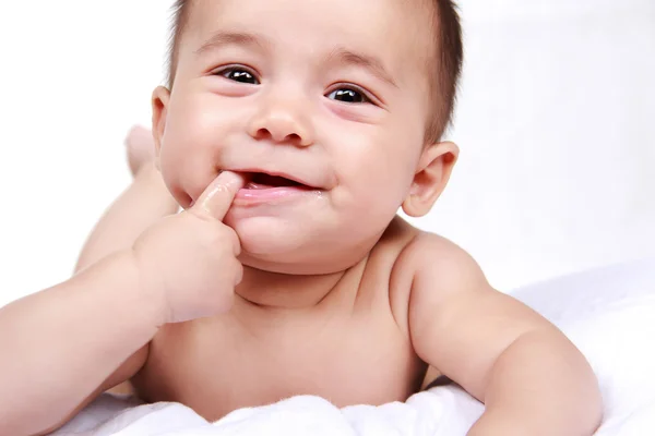 Søt liten baby som smiler mens han suger på de små fingrene sine – stockfoto