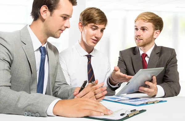Три бизнесмена обсуждают новый план в офисе — стоковое фото