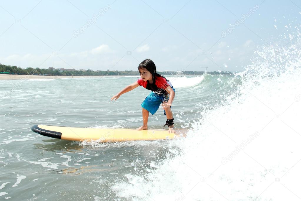 yooung boy learn to surf at ocean with splashing water