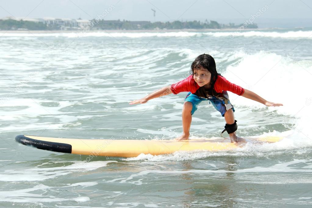 little boy learn to surf at ocean