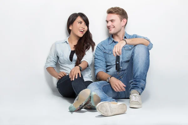 Mixed couple sitting on the floor. man embracing woman — Stockfoto