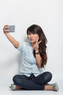 young woman sitting on the floor taking self camera