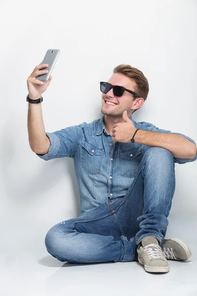 Young man sitting on the floor taking self camera — Zdjęcie stockowe